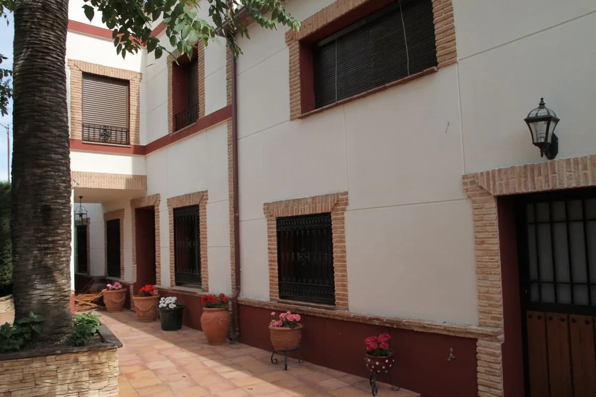 Fachada encalada de Tres Ventas con ladrillo visto y macetas