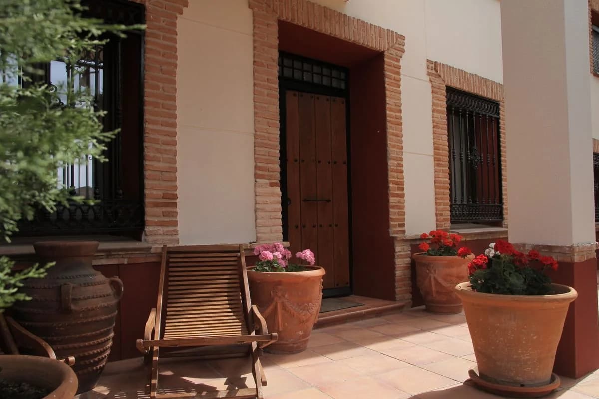 Tumbona de madera, tinaja y flores en el patio