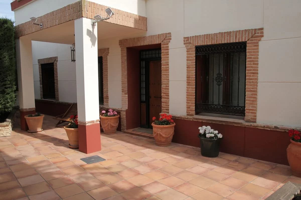 Patio con columna, macetas de flores y puerta de madera