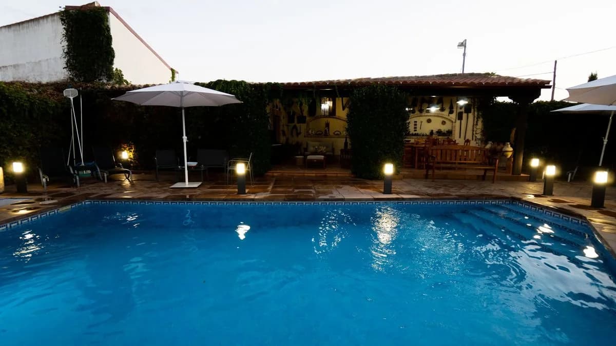 Piscina con el porche iluminado al anochecer