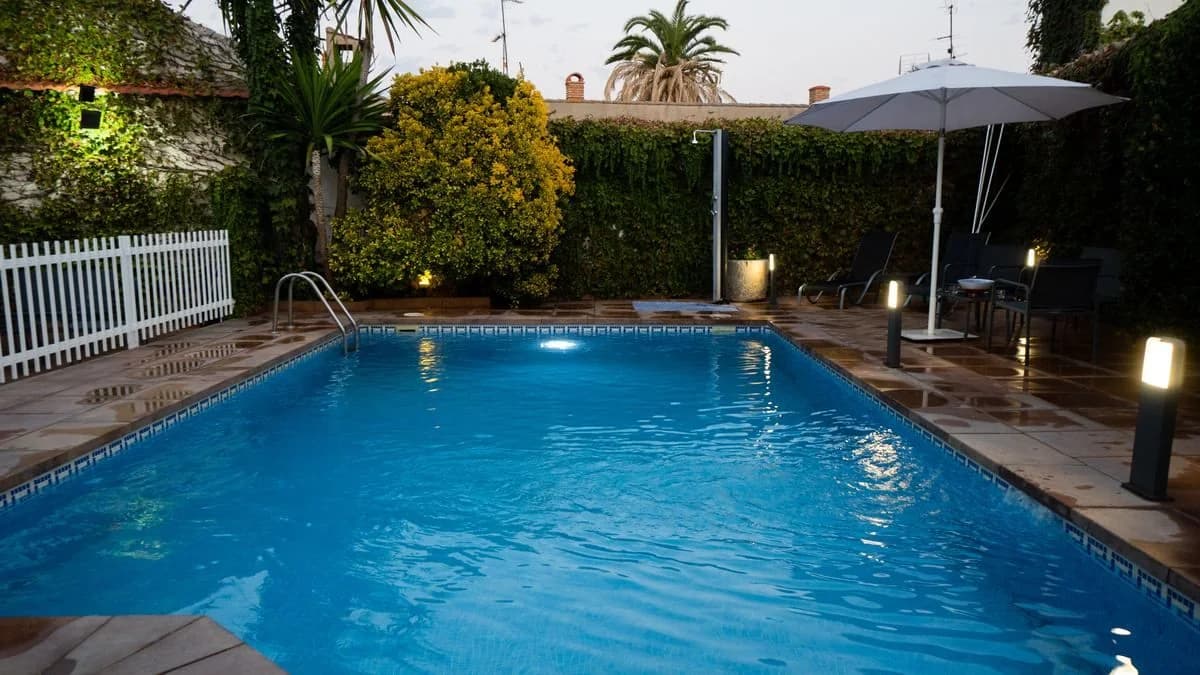 Piscina de Casa Rural Tres Ventas al atardecer, con sombrilla y tumbonas