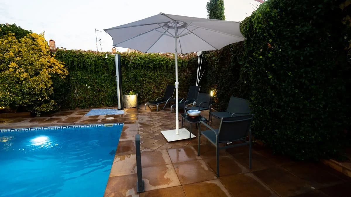 Piscina con sombrillas blancas y zona de estar